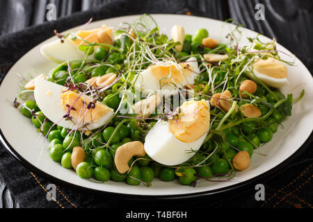 La vitamine Salade de pois verts, pousses, les noix et les oeufs sur une plaque horizontale sur la table. Banque D'Images