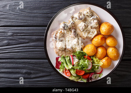 Escalope de porc en sauce crémeuse aux champignons avec une salade de pommes de terre fraîches et de légumes grillés sur une plaque horizontale. haut Vue de dessus Banque D'Images