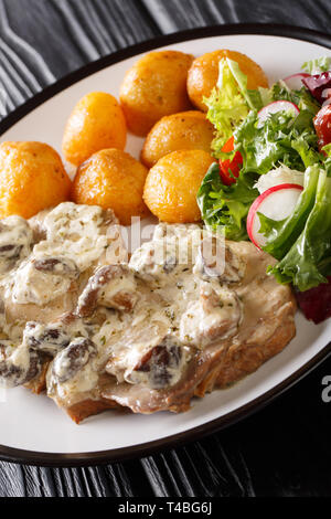 Escalope de porc en sauce crémeuse aux champignons avec une salade de pommes de terre fraîches et de légumes grillés sur une plaque verticale. Banque D'Images