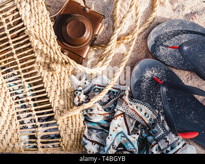 Panier en osier, vintage camera et châle sur fond de sable. Vue de dessus, close-up Banque D'Images