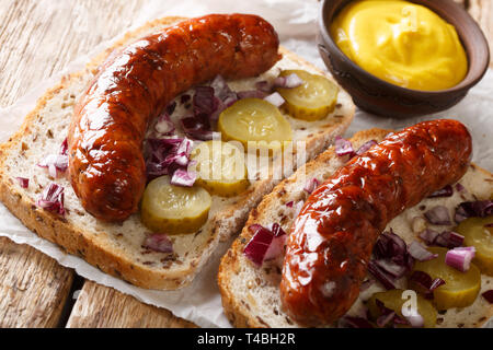 German street food La cuisine avec saucisses grillées, concombres, oignons et moutarde gros plan sur la table horizontale. Banque D'Images