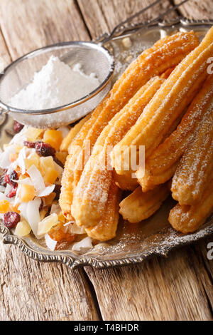 De délicieux churros maison de sucre glace et fruits confits close-up sur la table verticale. Banque D'Images