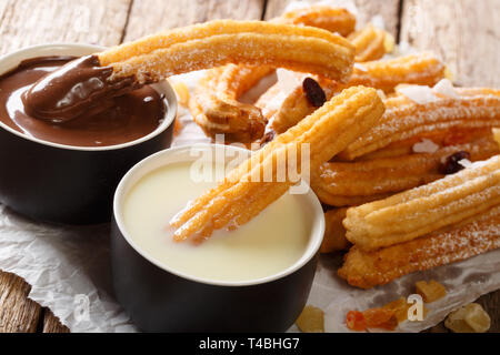 Dessert espagnol churros servi avec du chocolat chaud et de lait concentré sur la table horizontale. Banque D'Images