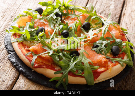 Restaurant gastronomique italien pizza au saumon, roquette, olives noires et fromage mozzarella close-up sur la table horizontale. Banque D'Images