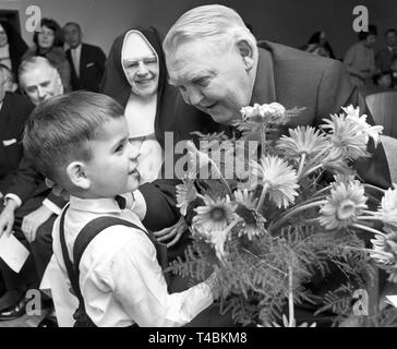 Chancelier Ludwig Erhard visites des orphelins dans un orphelinat à Bonn le 20 décembre en 1963, de les surprendre avec des cadeaux de Noël. La photo montre Ludwig Erhard, qui est accueilli par un petit garçon avec un bouquet de fleurs. Dans le monde d'utilisation | Banque D'Images