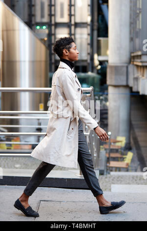 Vue latérale du jeune black businesswoman walking in the city, London UK, pleine longueur Banque D'Images