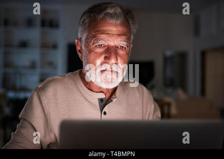 Senior Hispanic man ses finances en direct à la maison en utilisant un ordinateur portable pendant la nuit, Close up Banque D'Images