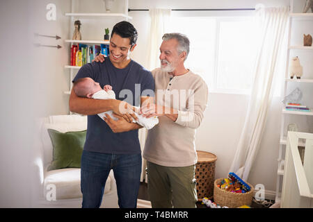 Fier senior Hispanic man standing avec son fils adulte en tenant son petit garçon de quatre mois Banque D'Images