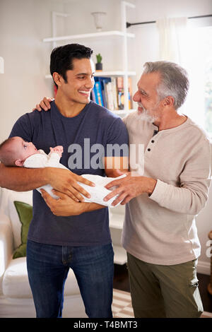 Fier senior Hispanic man standing avec son fils adulte en tenant son petit garçon de quatre mois, vertical Banque D'Images