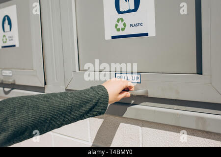Une personne ouvre ou ferme un bac moderne des déchets pour la collecte séparée des déchets. Banque D'Images