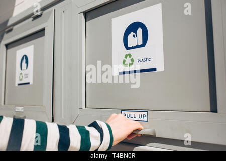 Une personne ouvre ou ferme un bac moderne des déchets pour la collecte séparée des déchets. Banque D'Images