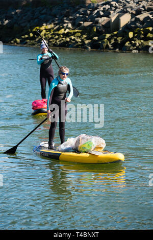 Deux femmes adultes on stand up paddleboards participant volontairement dans une rivière propre, décrochant le plastique et d'autres types des déchets, organisé par plage d'Aberystwyth Buddies / Gwerin y Glannau Rheidol le long de la rivière à Aberystwyth, Pays de Galles UK Banque D'Images