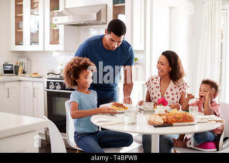 Jeune mère assis à table dans la cuisine avec les enfants, père de les servir la nourriture, selective focus Banque D'Images