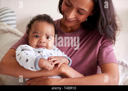 Close up of mixed race jeune jeune adulte mère tenant son bébé garçon dans ses bras, comme il ressemble à l'appareil photo Banque D'Images