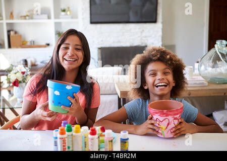Heureux fille préadolescente et sa petite amie holding plant pots qu'ils ont décoré avec des peintures à la maison, souriant à la caméra, Close up Banque D'Images