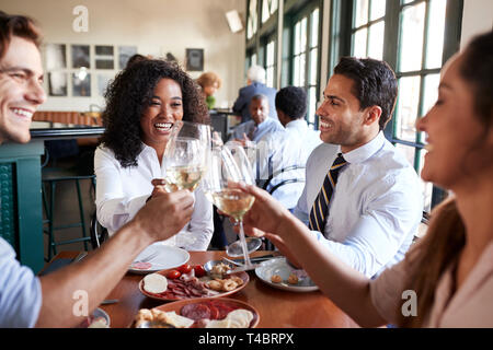 Des collègues de faire des toasts assis autour de la table de restaurant Repas de l'alimentation Banque D'Images