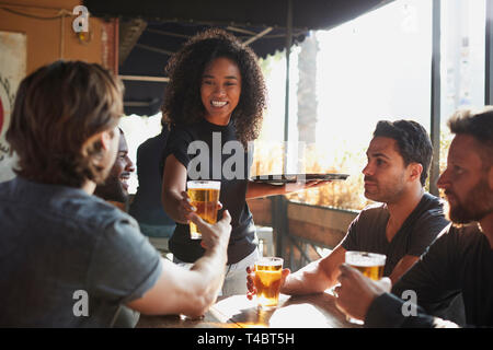 Serveuse servant des boissons au groupe d'amis en réunion Sports Bar Banque D'Images