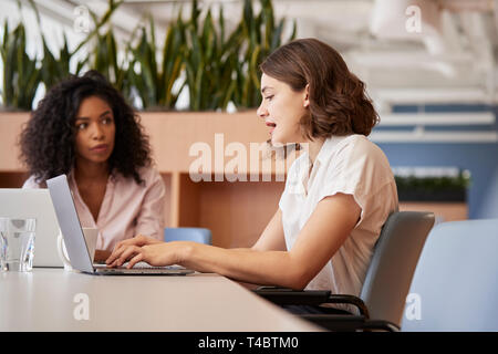 Two Businesswomen working on Laptops Sitting At Table in Modern Open Plan Office Banque D'Images