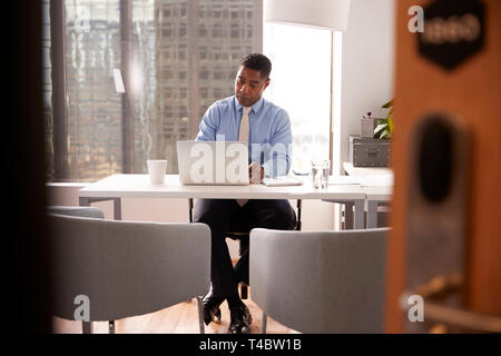 Conseiller financier à l'homme moderne Bureau Sitting At Desk Working On Laptop Banque D'Images