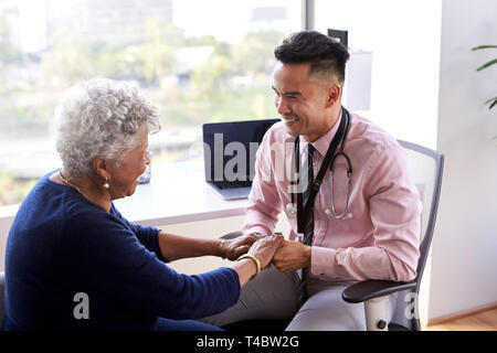 Doctor in Office rassurant Senior Female Patient et tenant ses mains Banque D'Images