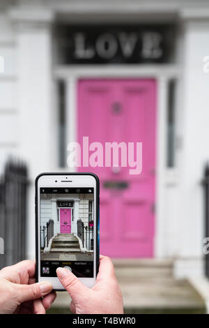 Prendre une photo sur un iPhone d'une maison rose porte avant avec amour sur la fenêtre dans Oakley Street, Kensington and Chelsea, Londres, Angleterre Banque D'Images