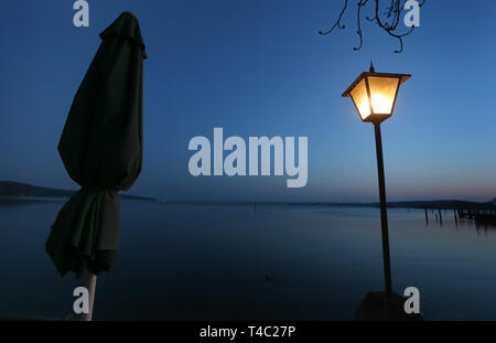 Manche, en Allemagne. Apr 15, 2019. Un parasol est à l'heure bleue dans un jardin au bord de l'Ammersee, à côté d'une lanterne. Credit : Karl-Josef Opim/dpa/Alamy Live News Banque D'Images