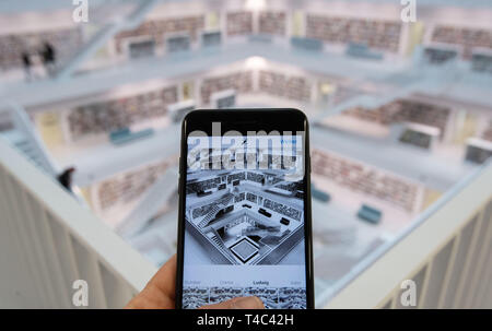 Stuttgart, Allemagne. 10 avr, 2019. Un homme dans la bibliothèque de la ville est l'édition d'une photo dans l'Instragram app sur son téléphone portable (que représentent les lieux). La Stadtbibliothek Stuttgart comme un hotspot'-'Instagram est confrontée à des défis. Il a été mentionné plus de 5000 fois et a déjà été utilisé ou a demandé qu'un motif pour mariages, photos et interviews du ventre de bébé. Credit : Marijan Murat/DPA - ATTENTION : Seulement pour un usage éditorial dans le cadre de rapports sur la Stadtbücherei Stuttgart./dpa/Alamy Live News Banque D'Images