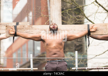 Birmingham, UK. 16 avril, 2019. Un contemporain le Christ est crucifié. Une équipe diversifiée d'une centaine de musiciens et acteurs communautaires, aux côtés d'intendants Saltine Theatre Company re-raconter l'histoire de Pâques dans une procession dans le centre-ville de Birmingham. La procession se termine à la Cathédrale St Philip's Peter Lopeman/Alamy Live News Banque D'Images