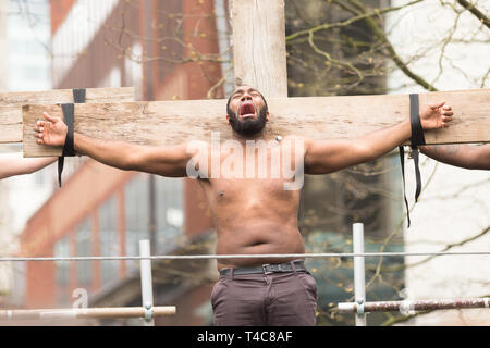 Birmingham, UK. 16 avril, 2019. Un contemporain le Christ est crucifié. Une équipe diversifiée d'une centaine de musiciens et acteurs communautaires, aux côtés d'intendants Saltine Theatre Company re-raconter l'histoire de Pâques dans une procession dans le centre-ville de Birmingham. La procession se termine à la Cathédrale St Philip's Peter Lopeman/Alamy Live News Banque D'Images