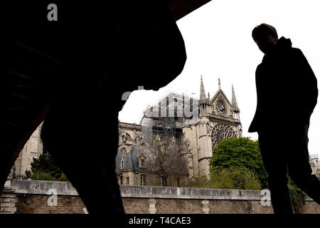 Paris, France. Apr 16, 2019. 16 avril 2019, la France (France), Paris : la silhouette d'un homme qui passe peut être vu en face de la cathédrale Notre-Dame en arrière-plan. Le lundi soir (15.04.2019) un incendie a éclaté dans la célèbre cathédrale Notre-Dame de Paris. Au-dessus du Monument il y avait des flammes et une énorme colonne de fumée. Un petit tour pointue dans le milieu du toit s'est effondré. Photo : Marcel Kusch/dpa dpa : Crédit photo alliance/Alamy Live News Banque D'Images