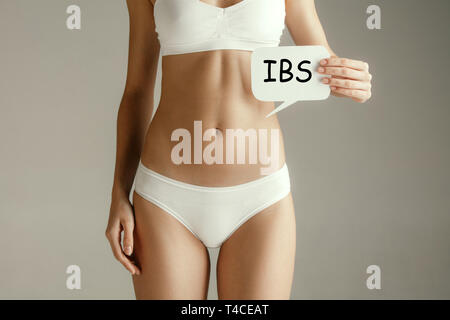 Concept d'estomac. La femme avec IBS texte gris sur fond de studio. Le syndrome du côlon irritable ou IBS concepts mois Banque D'Images