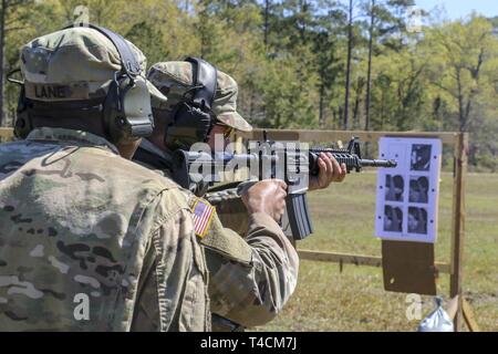 L'Armée Garde Nationale de Géorgie, le Sgt. Darius Lane, représentant la savane, 935e Bataillon de soutien à l'Aviation, observe qu'un participant se déplace dans un tir de combat forer en formation au petit calibre clinique Leaders à Fort Stewart, en Géorgie le 20 mars 2019. Les participants ont été chronométrés et classés sur la précision de leur tir tout en continuant à travailler sur des techniques de combat à l'aide de la carabine M4. U.S. Army National Guard Banque D'Images