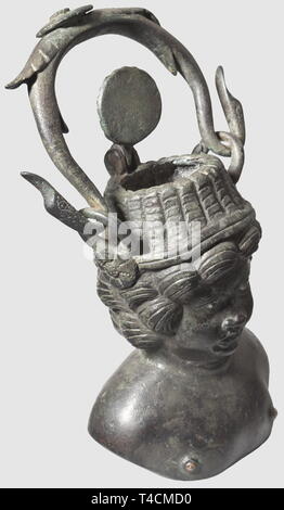 Un balsamarium romain, 1ère/2ème siècle AD. Bronze avec patine verdâtre. Contenant dans la forme d'un buste d'un Cupidon portant un chapeau de paille. Modélisé finement les traits du visage, yeux incrustés d'argent et les tétons. Haut de la hat avec couvercle à charnière. Boucles latérales avec des rosettes. La poignée amovible à destination de chefs de l'oiseau. La boucle droite légèrement endommagé, petit trou à l'arrière de la tête. Hauteur sans couvercle 10 cm, avec couvercle 14,5 cm. Provenance : Collection privée, Vienne 1980, historique, historique, 20e siècle, l'Ancien Monde, monde antique, Additional-Rights Clearance-Info-ancie,-Not-Available Banque D'Images