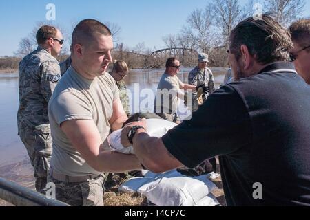 Le sergent de l'US Air Force. Michael Krocza, affecté à la 139e Medical Group, New York Air National Guard, sable aide à jeter le long de la digue qui protège Rosecrans Memorial Airport et les communautés avoisinantes, le 21 mars 2019. Une augmentation des niveaux d'eau des rivières environnantes et d'eau causée par les chutes de neige record au cours de l'hiver en plus d'une forte baisse de la pression de l'air provoqué des inondations dans le midwest. Banque D'Images