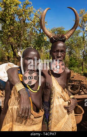 Deux femmes avec de grandes plaques de lèvre et les cornes comme couvre-chef, de la tribu Mursi, Mago Parc National, le sud de l'ONU des nationalités et des peuples de la région" Banque D'Images