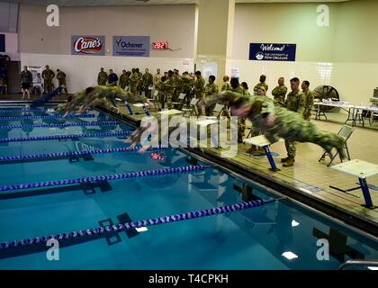 La Nouvelle Orléans (22 mars 2019) Servicemembers stationnées dans le plus grand secteur de la Nouvelle-Orléans, en Louisiane sauter dans une piscine tout en essayant de se qualifier pour les Forces armées allemandes pour Badge de compétence militaire à l'Université de New Orleans Centre aquatique du 22 mars. Les Forces armées allemandes d'un insigne pour les militaires officielles est l'une des plusieurs centaines de bourses étrangères approuvées pour l'usure sur les uniformes militaires des États-Unis. Pour être admissibles, les participants sont testés dans leurs prouesses physiques, adresse au tir, les premiers soins, et les connaissances des armes nucléaires, biologiques et chimiques. Banque D'Images