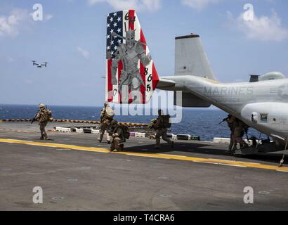 Golfe d'ADEN (23 mars 2019) - Marines des États-Unis avec la 22e Marine Expeditionary Unit assurent la sécurité en sortant une MV-22 Osprey dans le poste de pilotage de la classe Wasp-navire d'assaut amphibie USS Kearsarge (LHD-3) lors d'une récupération d'aéronefs tactiques et de répétition de missions du personnel. La formation prépare à entrer dans les zones marines combatif et récupérer ou détruire des matériaux sensibles ainsi que la reprise du personnel. Marines et de marins avec la 22e MEU et Amphibie Kearsarge Groupe sont actuellement déployés dans le domaine de la 5e flotte américaine des opérations à l'appui des opérations navales pour assurer mari Banque D'Images