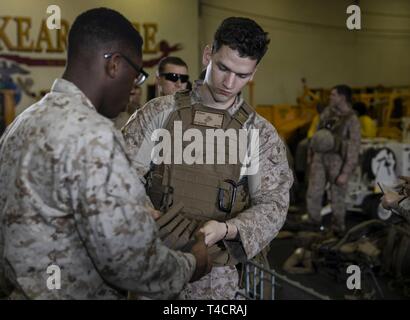 Golfe d'ADEN (23 mars 2019) - U.S. Marine Lance Cpl. Sean Coughlin, droite, un mitrailleur, renvoie ses munitions pour le Cpl. Zarian Lang, un technicien de munitions, tant avec la 22e unité expéditionnaire de marines, dans le pont du coffre de la classe Wasp-navire d'assaut amphibie USS Kearsarge (LHD-3) après le retour d'une récupération d'aéronefs tactiques et de répétition de missions du personnel. La formation prépare à entrer dans les zones marines combatif et récupérer ou détruire des matériaux sensibles ainsi que la reprise du personnel. Marines et de marins avec la 22e MEU et Amphibie Kearsarge Groupe depl Banque D'Images