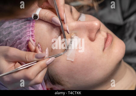 Procédure d'extension de cils. Les yeux des femmes de longs cils. Les cils, close-up, selective focus. Esthéticienne professionnelle, faire les cils artificiels Banque D'Images