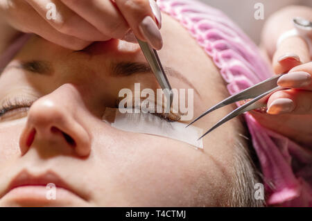 Procédure d'extension de cils. Les yeux des femmes de longs cils. Les cils, close-up, selective focus. Esthéticienne professionnelle, faire les cils artificiels Banque D'Images