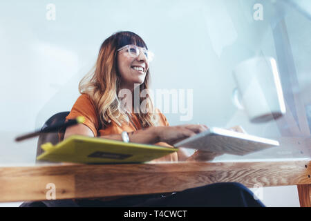 Close up d'un artiste créateur travaillant sur ordinateur dans bureau. Low angle view of a woman la saisie sur un clavier sans fil assise à son verre transparent Banque D'Images