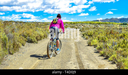 Femme équitation un vélo de montagne par un chemin boueux de la saleté. Le sport sain sur la campagne. Banque D'Images