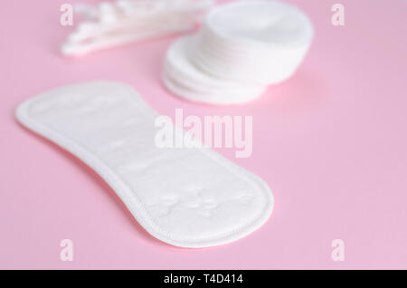 Produits d'hygiène. Tampons de coton, des serviettes hygiéniques et des bâtonnets d'oreille coton sur fond rose pastel Banque D'Images