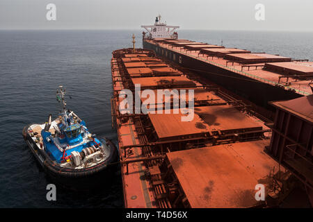 La gestion et le transport de minerai de fer. En attente de déchargement du minerai d'amendes en attente de TGV transhipper océaniques OGV navire en mer. Tug boat en veille. Banque D'Images