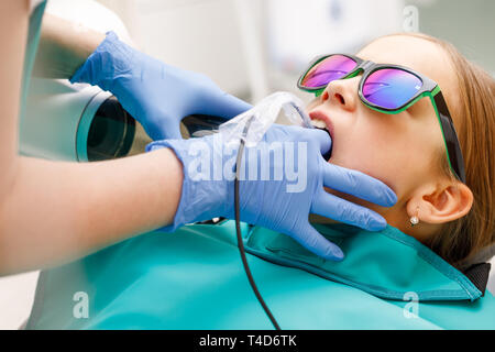 Manipulateur en radiologie à dents prenant de l'âge primaire girl using digital x-ray machine en clinique dentaire pédiatrique. Médecin faisant des rayons X, tandis que Banque D'Images