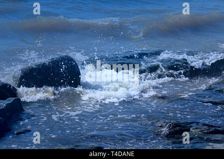 Blue vagues se brisant sur les roches du littoral par la mer. Banque D'Images