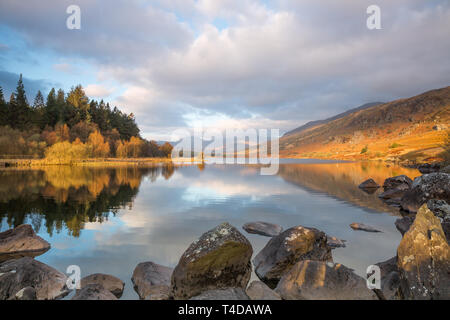 Moody, vue panoramique sur les montagnes Snowdon Horseshoe au lever du soleil, dans les nuages reflétés dans les eaux fixes de Llynnau Mymbyr, parc national de Snowdonia, pays de Galles, Royaume-Uni. Banque D'Images