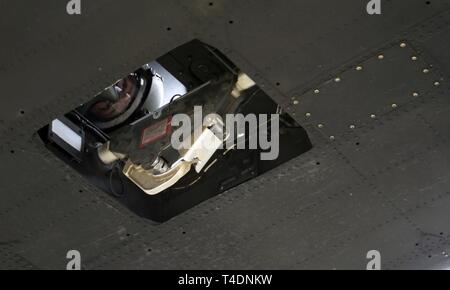 La CPS. Aaron Winberg, UH-60 Blackhawk membre de l'équipage de l'hélicoptère, regarde à travers le trou que son avion cargo plane au-dessus des soldats et des sacs sur le sol près de Gênes, New York le 23 mars. Winberg et le reste de son équipage volaient de sable, air drop missions au barrage de dérivation de la rivière Loup. La Garde Nationale (Nebraska Banque D'Images