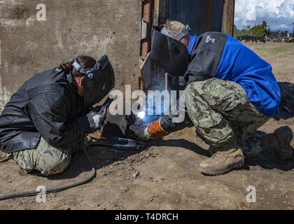 OXNARD, Californie (Mar. 20, 2019) - U.S. Navy métallo du 2e classe Gabriella Gonzalez (à gauche), de Lompoc, en Californie et Builder 3 classe Tyler Hunt, de Tucson, Arizona, tous deux assignés à l'unité d'entretien Construction Battalion 303 (CBMU-303), souder un pad eye pour un corps expéditionnaire quai patch (Patch) Curley de le préparer pour la soudure au cours d'un essai de preuve de concept de base navale à bord du comté de Ventura à l'appui du Blitz du Pacifique 2019 (PacBlitz19). La technique offre patch Curley réparation rapide de jetées et de quais permettant aux forces militaires de continuer à utiliser le port d'apporter un appui logistique Banque D'Images