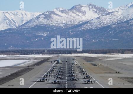 F-22 Raptors à partir de la 3e Escadre et 477th Fighter Group participent à une formation serrée avec un taxi E-3 Sentry et un C-17 Globemaster III, connu comme un éléphant à pied, le 26 mars 2019, au cours d'un exercice de la Force polaire at Joint Base Elmendorf-Richardson, en Alaska. Cet exercice de deux semaines d'escadrons donne l'occasion de démontrer leurs capacités à l'avant de déployer et de livrer combat écrasante. Banque D'Images